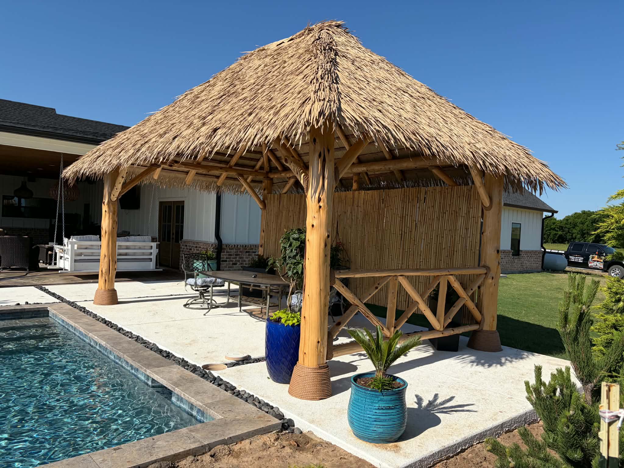 Round cedar-post palapa with natural palm thatch beside a pool