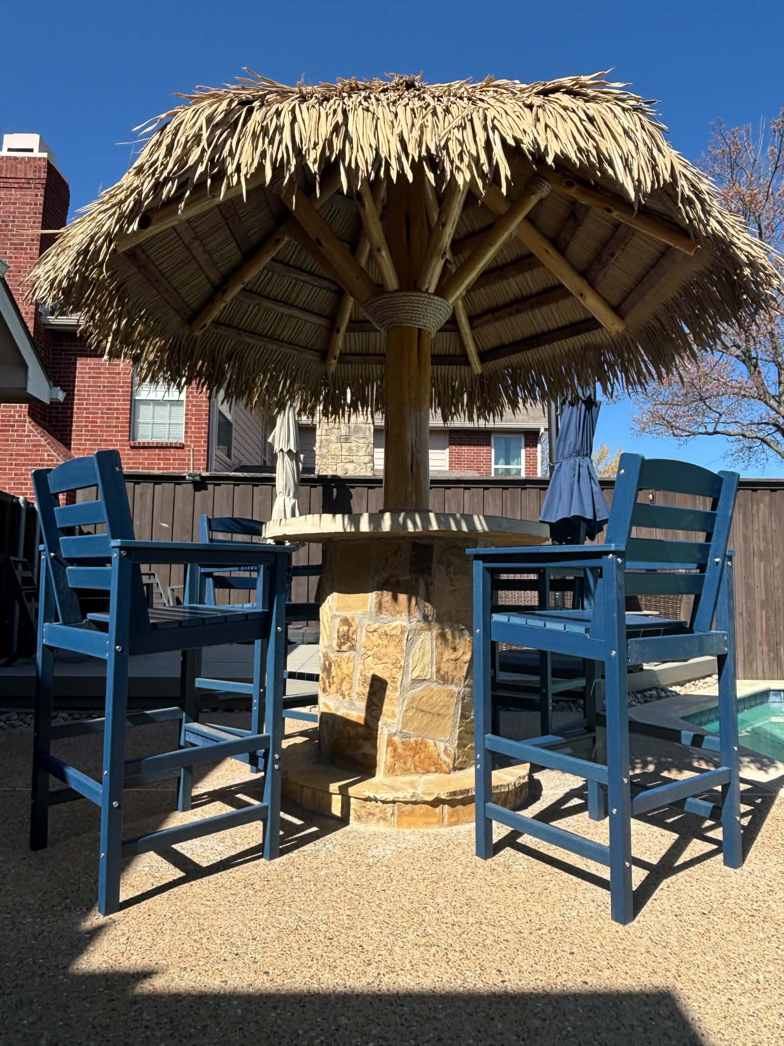 Single-post palm umbrella palapa shading poolside lounge chairs